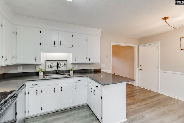 kitchen with light hardwood / wood-style floors, white cabinetry, kitchen peninsula, a textured ceiling, and sink