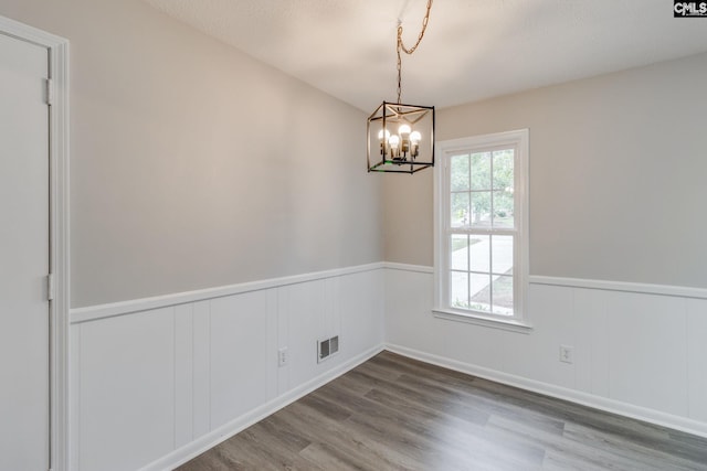 empty room featuring a notable chandelier, a textured ceiling, and hardwood / wood-style flooring