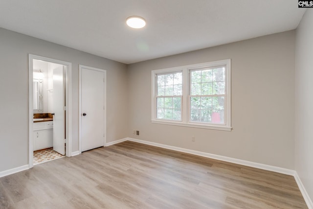 unfurnished bedroom with light wood-type flooring and ensuite bathroom