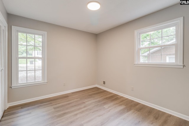 empty room with light hardwood / wood-style flooring and a wealth of natural light