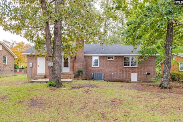 back of house with central air condition unit and a yard