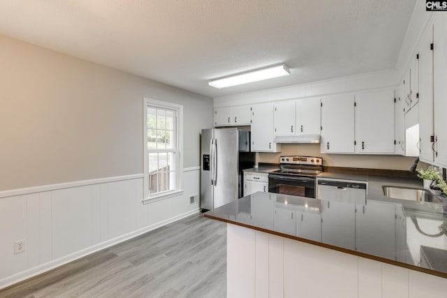 kitchen featuring appliances with stainless steel finishes, kitchen peninsula, light wood-type flooring, and white cabinets