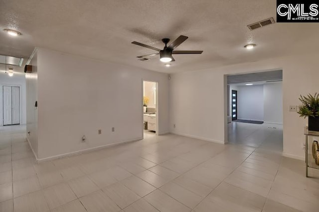 unfurnished room with ceiling fan and a textured ceiling