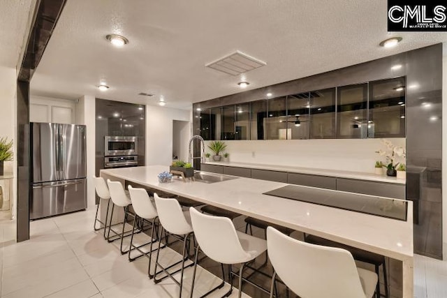 kitchen featuring appliances with stainless steel finishes, a textured ceiling, sink, and light tile patterned floors