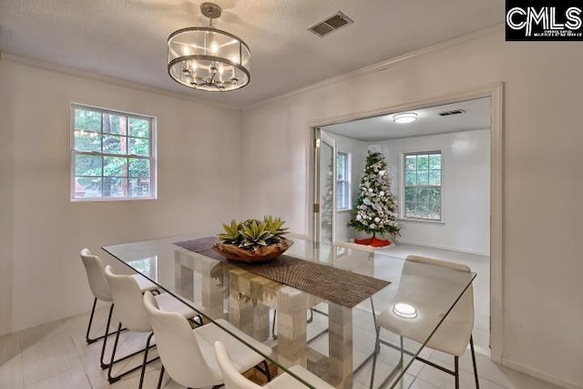 dining area with a textured ceiling, ornamental molding, and a chandelier