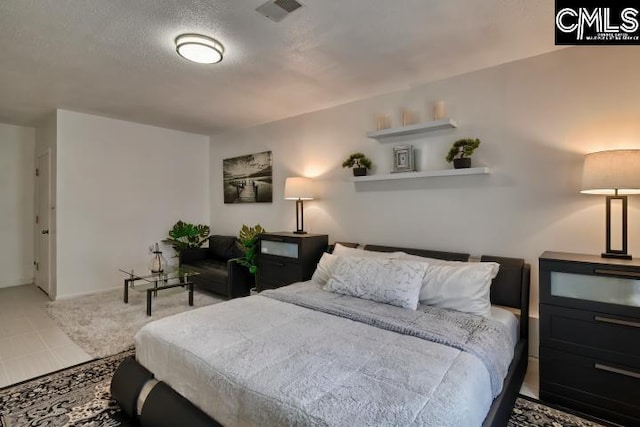 bedroom featuring light tile patterned flooring and a textured ceiling