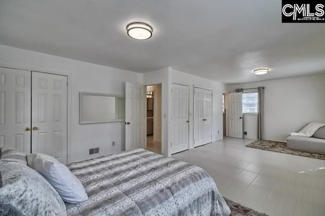 tiled bedroom featuring multiple closets