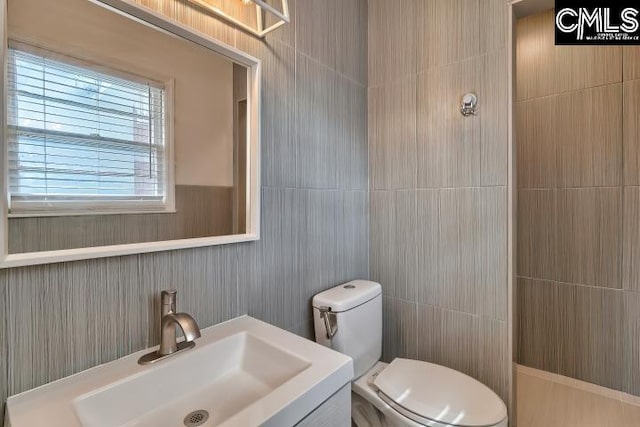 bathroom featuring tile walls, vanity, and toilet