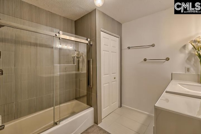 bathroom with tile patterned flooring, a textured ceiling, vanity, and bath / shower combo with glass door