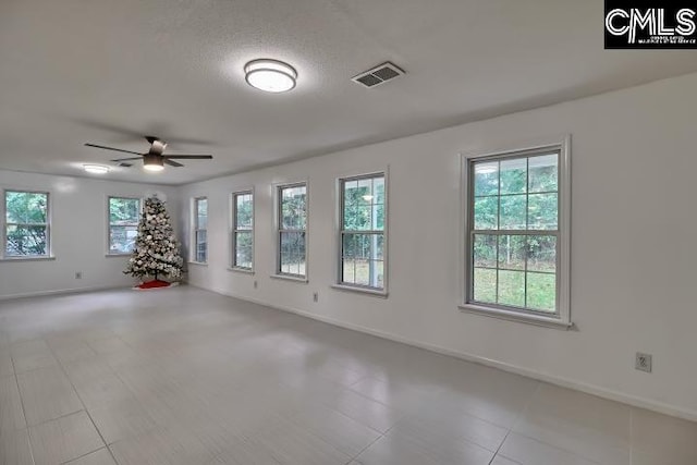 spare room with a textured ceiling, ceiling fan, and plenty of natural light