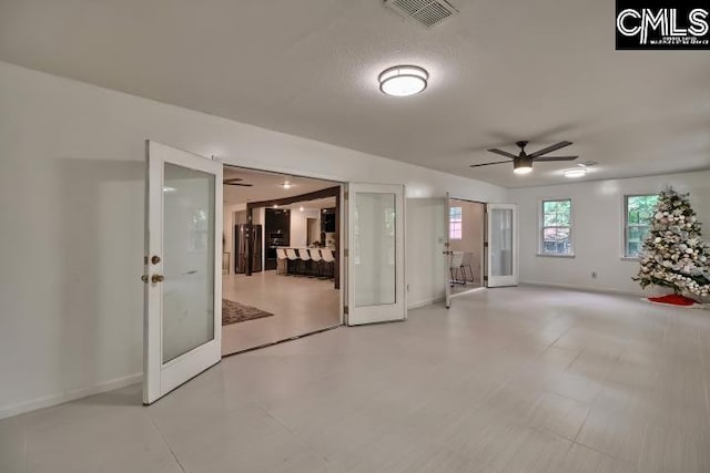 empty room with ceiling fan and a textured ceiling