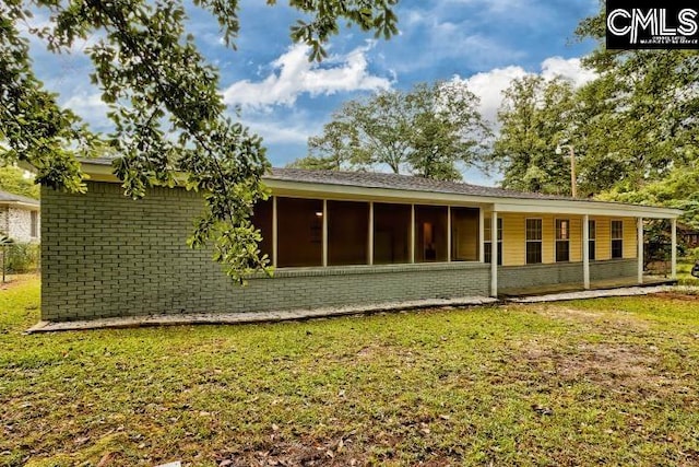 rear view of property with a lawn and a sunroom