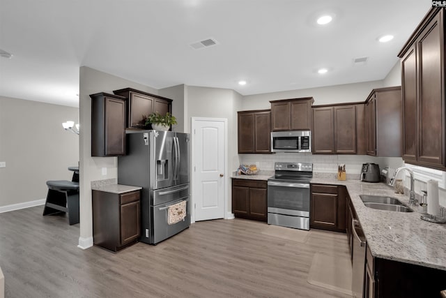 kitchen featuring dark brown cabinetry, light hardwood / wood-style floors, appliances with stainless steel finishes, and sink