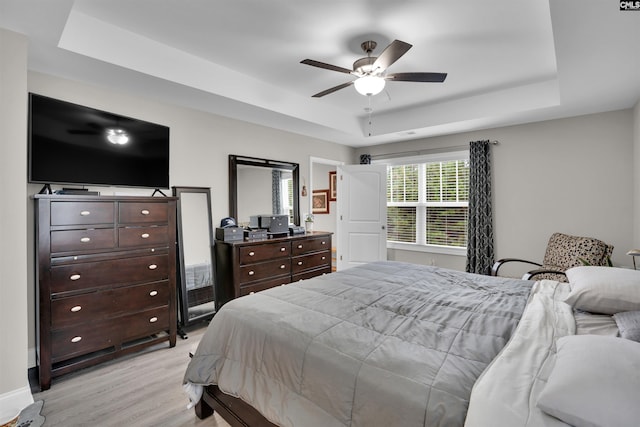 bedroom featuring a raised ceiling, ceiling fan, and light hardwood / wood-style flooring