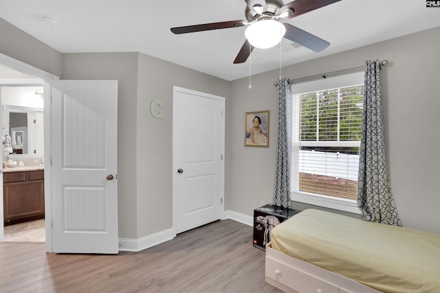 bedroom with light wood-type flooring, ceiling fan, and connected bathroom