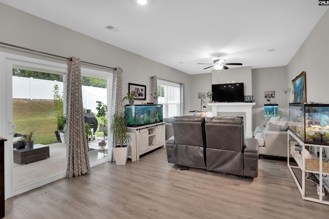 living room featuring light hardwood / wood-style flooring, ceiling fan, and a wealth of natural light