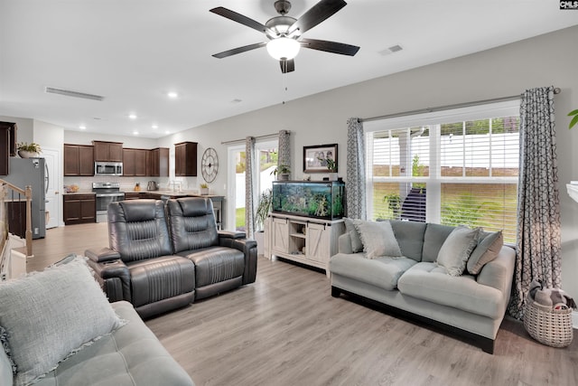 living room featuring ceiling fan, light hardwood / wood-style floors, and a wealth of natural light