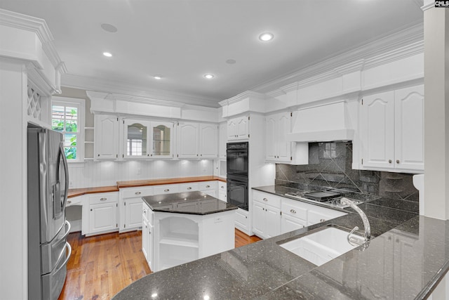 kitchen featuring light hardwood / wood-style floors, white cabinets, a kitchen island, appliances with stainless steel finishes, and ornamental molding