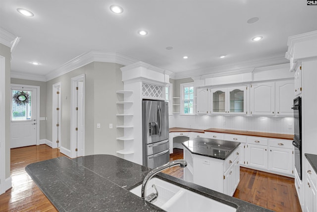 kitchen featuring white cabinetry, plenty of natural light, a kitchen island, and stainless steel fridge