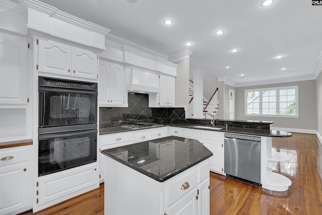 kitchen with a kitchen island, appliances with stainless steel finishes, light wood-type flooring, and white cabinetry