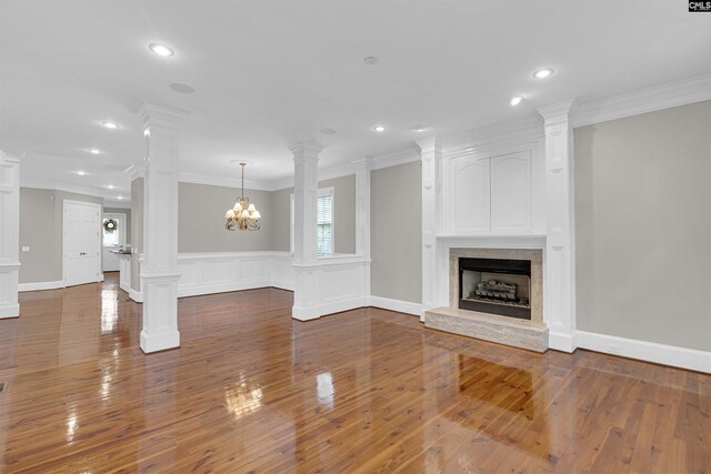 unfurnished living room featuring a premium fireplace, decorative columns, and dark hardwood / wood-style floors