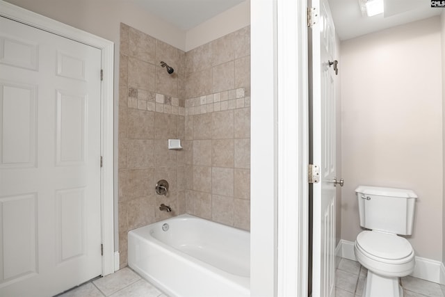 bathroom featuring tiled shower / bath, tile patterned flooring, and toilet