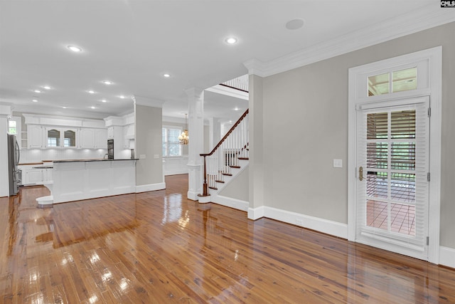 foyer with decorative columns, ornamental molding, and hardwood / wood-style floors