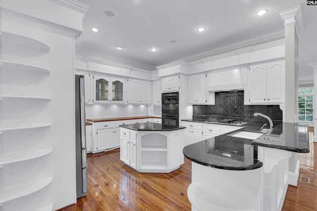 kitchen featuring custom exhaust hood, a kitchen island, light hardwood / wood-style floors, and white cabinetry