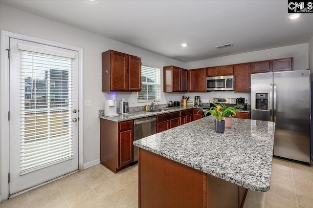 kitchen featuring appliances with stainless steel finishes, a sink, visible vents, and light stone countertops