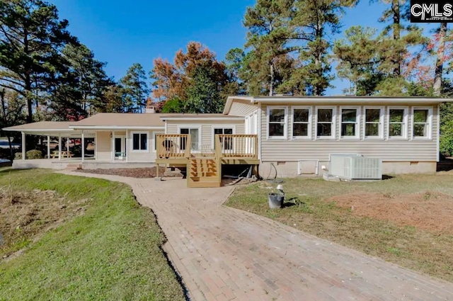 back of house with central AC unit, a carport, a deck, and a yard