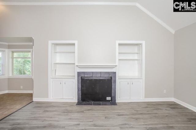 unfurnished living room featuring built in shelves, a fireplace, light hardwood / wood-style flooring, high vaulted ceiling, and ornamental molding