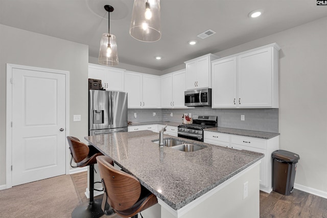 kitchen featuring decorative backsplash, dark wood-type flooring, an island with sink, white cabinets, and stainless steel appliances