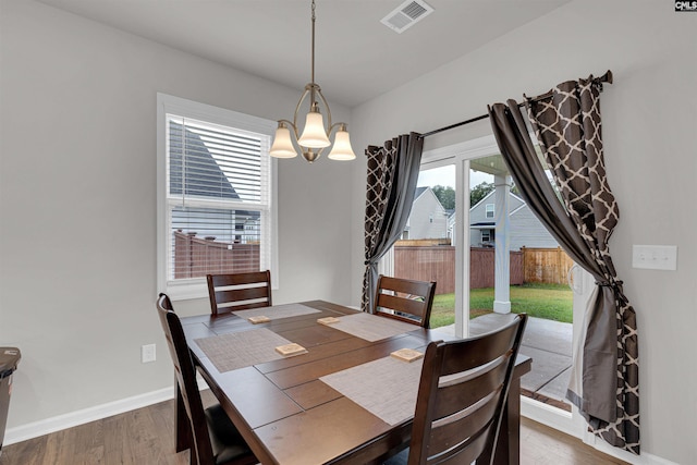 dining area with wood-type flooring and an inviting chandelier