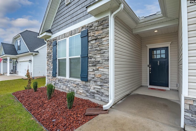 view of exterior entry featuring a lawn and a garage