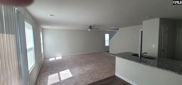 unfurnished living room with sink, dark carpet, and ceiling fan