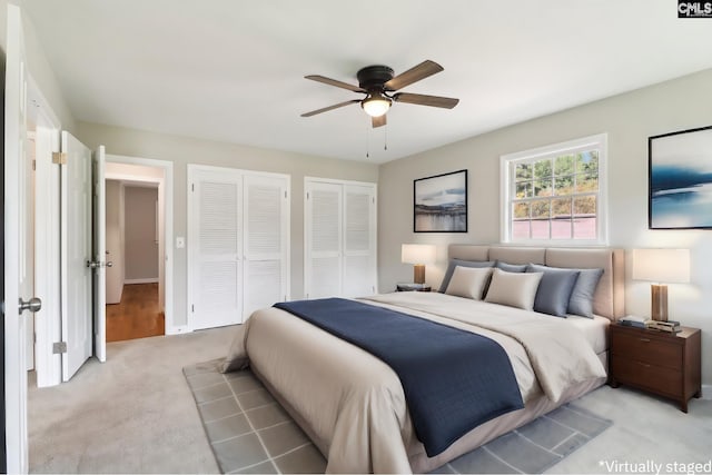 carpeted bedroom featuring ceiling fan and multiple closets