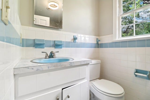 bathroom featuring tile walls, vanity, and toilet