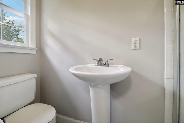 bathroom with a shower with door, toilet, and sink