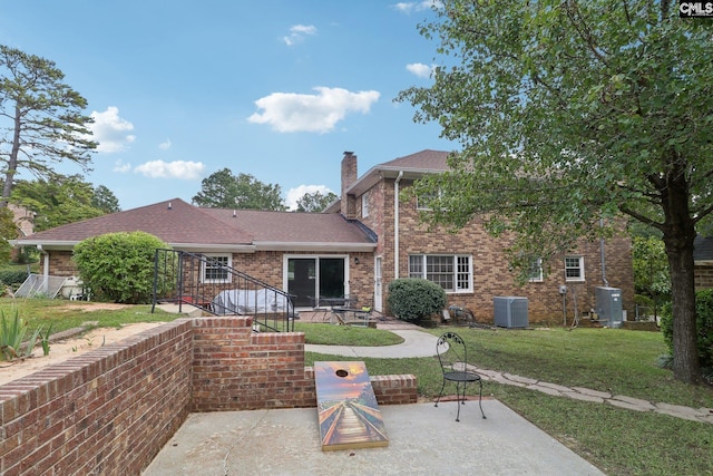 rear view of property with a patio, a yard, and central AC