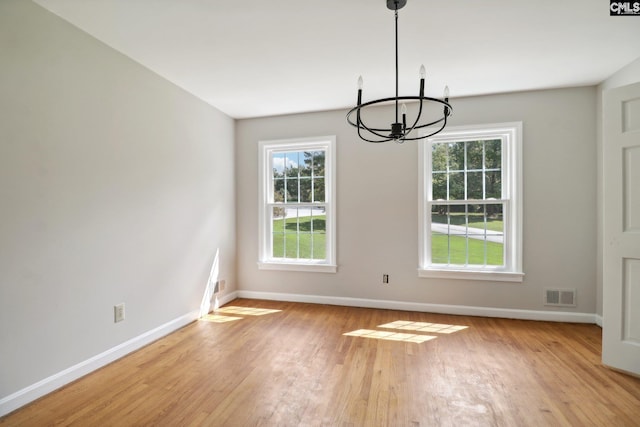 spare room with a notable chandelier and light hardwood / wood-style floors