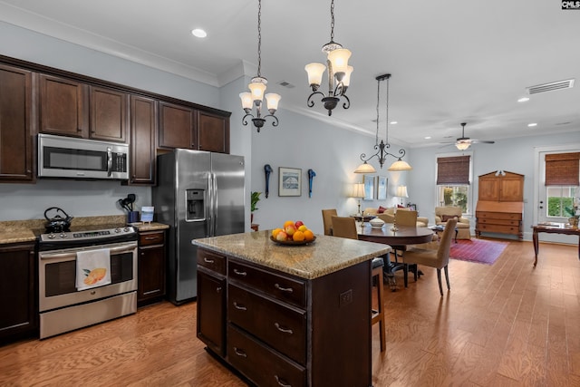 kitchen featuring ceiling fan with notable chandelier, a center island, appliances with stainless steel finishes, and hanging light fixtures