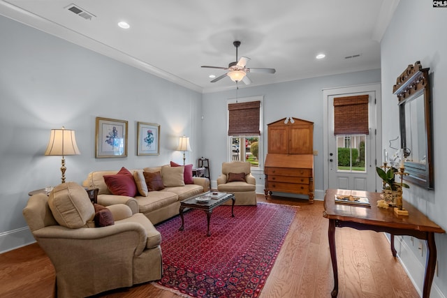 living room featuring wood-type flooring, crown molding, and ceiling fan