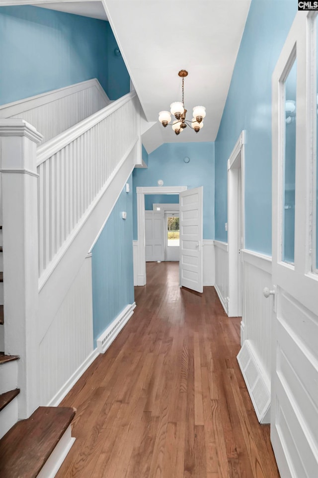 hallway featuring a notable chandelier, vaulted ceiling, and hardwood / wood-style flooring