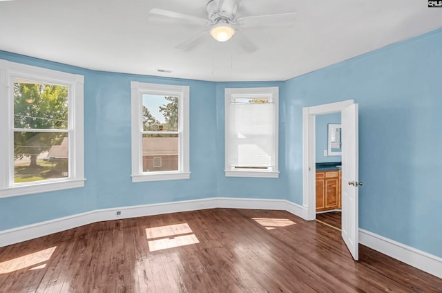 empty room with ceiling fan and dark hardwood / wood-style flooring