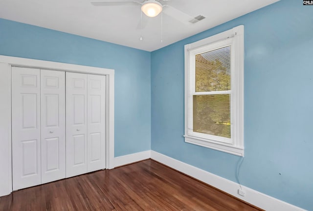 unfurnished bedroom featuring dark hardwood / wood-style flooring, ceiling fan, and a closet