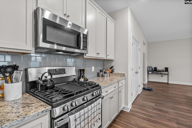 kitchen with light stone counters, dark hardwood / wood-style floors, stainless steel appliances, and white cabinets