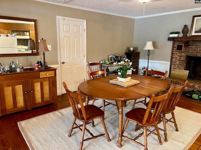 dining room with a textured ceiling, a fireplace, ornamental molding, and dark hardwood / wood-style floors