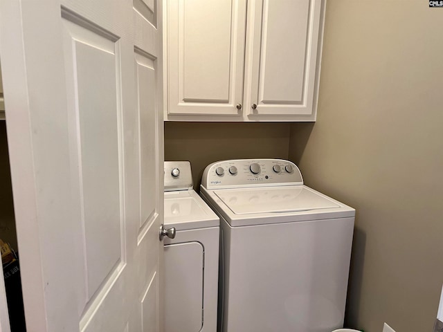 clothes washing area with separate washer and dryer and cabinets