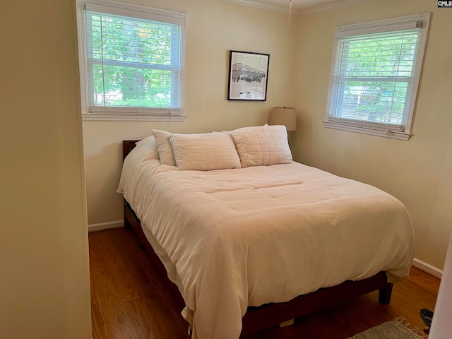 bedroom featuring multiple windows, crown molding, and dark wood-type flooring