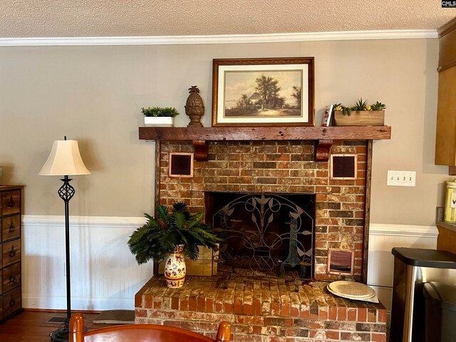 living room with a brick fireplace, a textured ceiling, and crown molding